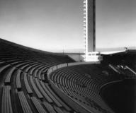 Mustavalkoinen kuva vanhoista stadionin penkeistä ja tornista