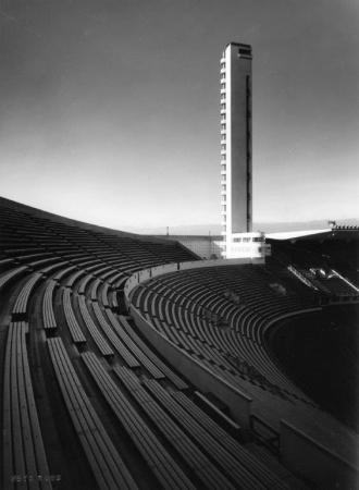 Mustavalkoinen kuva vanhoista stadionin penkeistä ja tornista